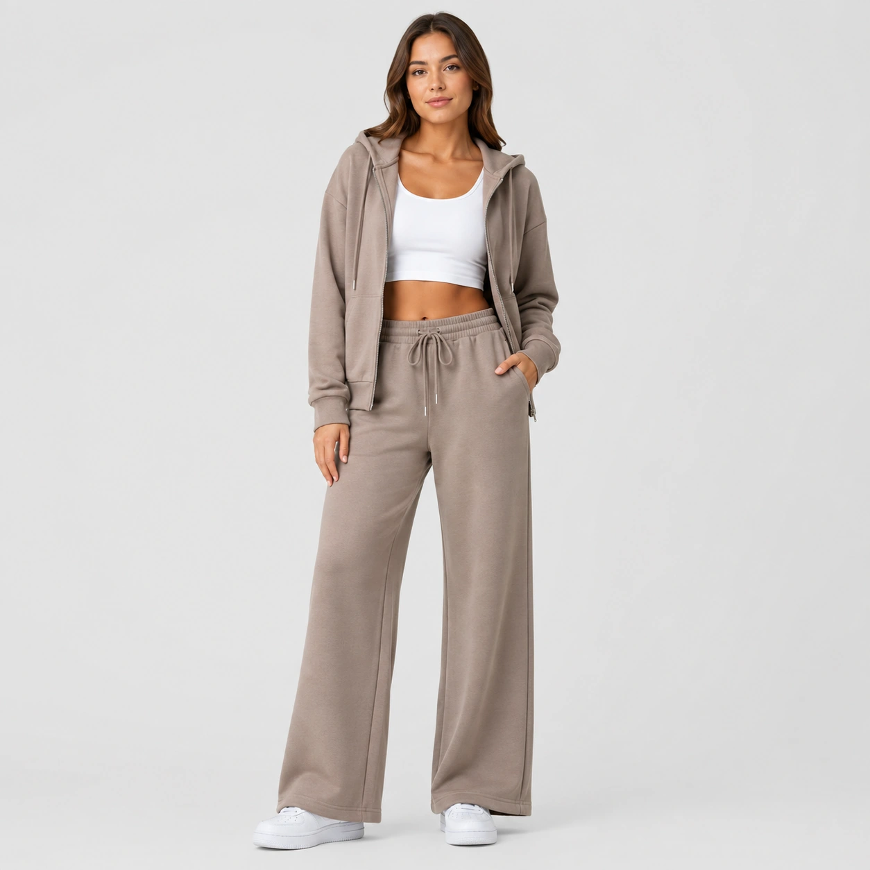 Woman wearing an oatmeal lounge hoodie and matching pants on a white background