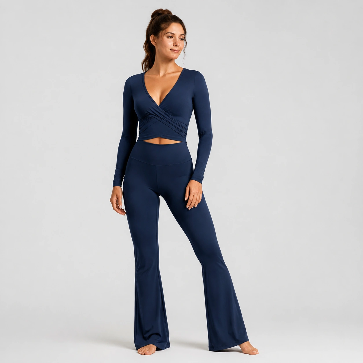 Woman wearing navy flare pants and a wrap studio top on a white background