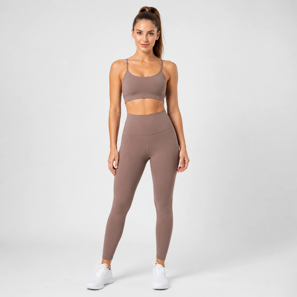 Woman wearing sage sports bra and black yoga leggings on a white background